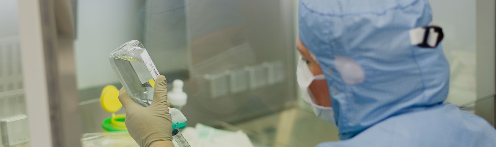 Ein Mediziner in Schutzkleidung bereitet in einem Labor sorgfältig eine Infusion vor, um Krebspatienten zu behandeln.