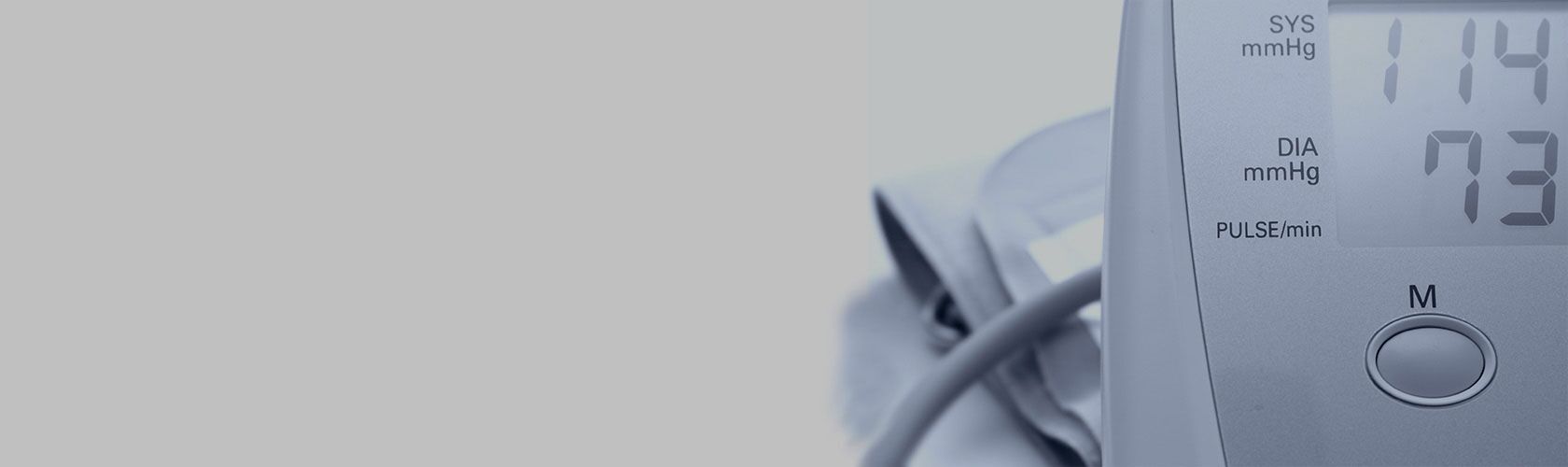 Ein Blutdruckmessgerät zeigt Werte von 114 zu 73 mmHg auf einem digitalen Display an.